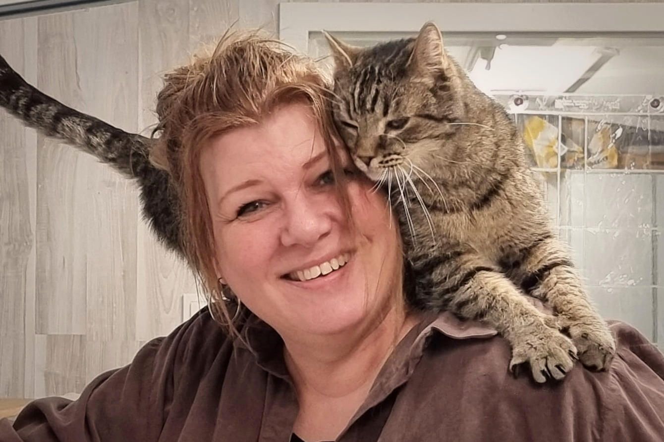 Betreuerin der Katzenpension mit einer getigerten Katze auf der Schulter